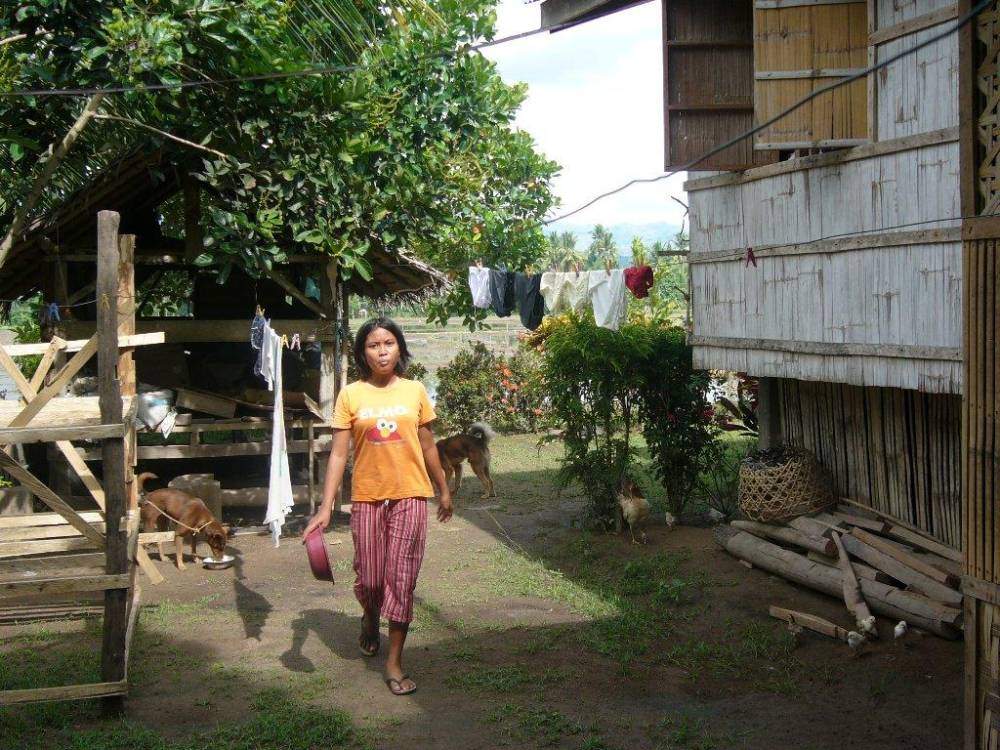 Mindanao farm girl feeding the dogs and chickens