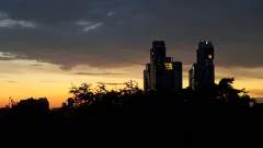 A couple of tall buildings silhoetted against the first light of dawn